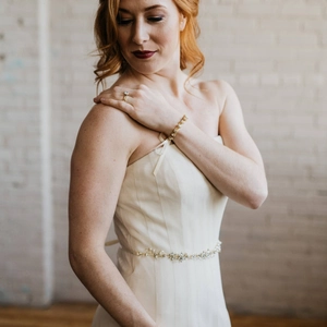Détail d'une ceinture de mariée avec strass et perles sur une robe de mariée blanc ivoire