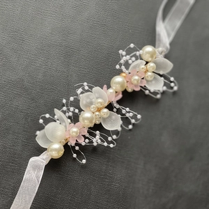 Dettaglio fascia da sposa artigianale con perle, petali satinati e nastro di seta bianca