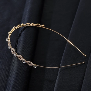 Close-up of golden bridal headband with sparkling rhinestones on black silk fabric