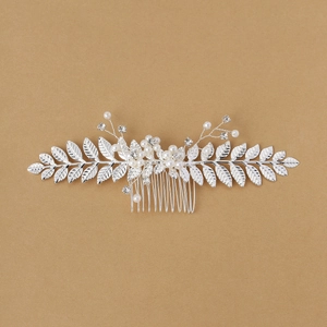 Détail de peigne à cheveux mariée avec feuilles argentées, perles et cristaux brillants