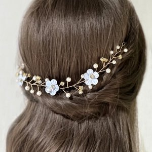Detail of white fabric flowers and pearls on a flexible gold wire wedding hair chain