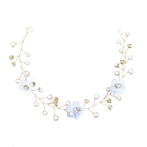 Close-up of gold hair vine with blue fabric flowers, pearls, and sparkling crystals