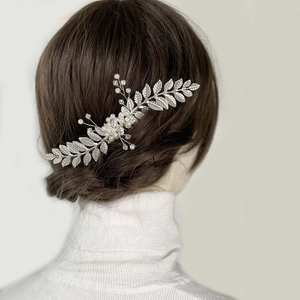 Détail d'un peigne à cheveux argenté avec feuilles, perles et cristaux pour mariée