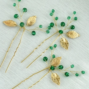 Detailed view of handmade golden leaf U-shaped hairpins with emerald green crystal beads