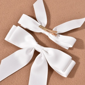 Pair of white satin bow hair clips for bridal wedding photography with gold metal duckbill clips
