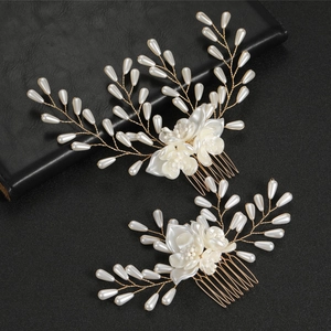 Dettaglio dei pettini per capelli con fiori di perle bianche e filo d'oro su nero