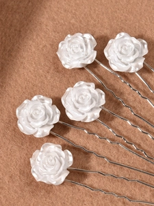 Close-up of five white camellia hair pins with pearlescent petals and silver U-shaped metal clips