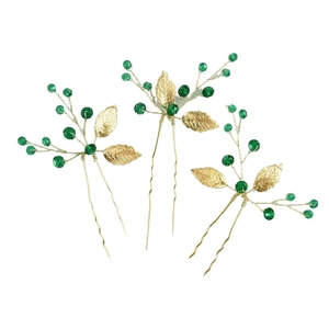 Detailed view of three gold leaf hair pins with green beads and twisted wire stems