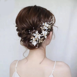 Handmade bridal hairpiece with white flowers, gold leaves, and pearls on elegant updo
