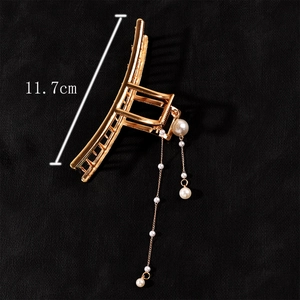 Detail view of a 11.7cm large gold metal hair claw with elegant pearl tassel pendants