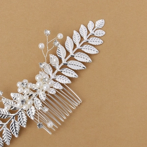 Détail d'un peigne à cheveux de mariée argenté avec feuilles, perles et cristaux