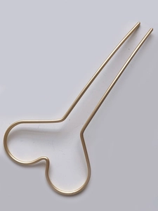 Détail d'un pic à cheveux minimaliste en métal doré avec haut incurvé et design à double broche