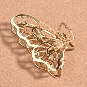 Gros plan de la pince à cheveux papillon en métal doré avec motifs d'ailes ajourés