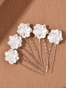 Detail view of five white camellia U-shaped hair pins with glossy pearl finish on felt