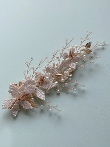 Detailed macro view of handmade bridal hairpiece with pearls, crystals, and gold leaves