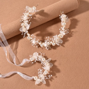 Dettaglio di accessori per capelli da sposa con petali opachi, perle e filo dorato su feltro