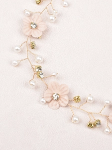 Detailed close-up of golden bridal hair vine with pink fabric flowers and pearls