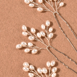 Macro shot of handcrafted bridal hair pins featuring white pearls and silver wire weaving