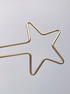 Gros plan d'une épingle à cheveux étoile dorée minimaliste en fil métallique poli