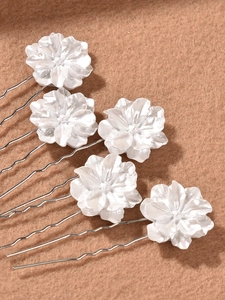 Detailed macro view of five pearl white camellia hair pins with silver wavy U-shaped grips