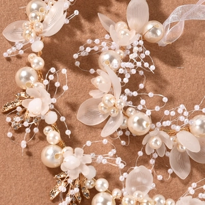 Dettaglio accessorio capelli sposa con perle bianche, petali in resina e fili dorati