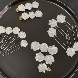 Detail of white camellia floral hair clips and hairpins on a black round tray