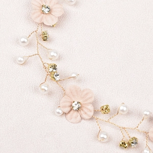 Macro detail of bridal flower hair chain with pink cloth petals, pearls and gold wire