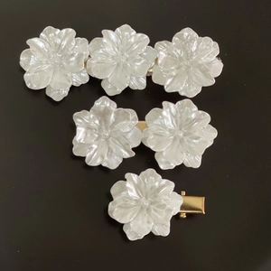 Detail view of pearl white camellia hair clips with gold metal duckbill clamps