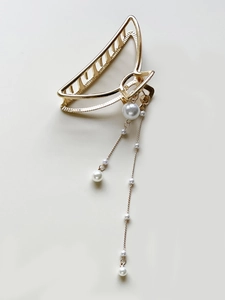 Detailed view of champagne gold shark hair clip with hanging pearl tassel pendants