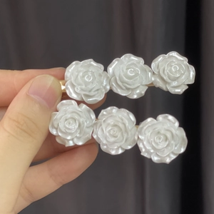 Elegant pair of gold hair clips with three pearlescent white camellia flowers on each pin
