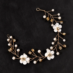 Detail of white fabric flowers and sparkling crystals on a golden bridal hair vine
