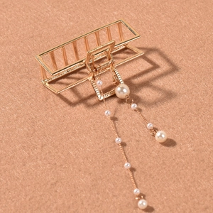 Detailed view of golden rectangle hair claw clip with elegant hanging pearl tassels