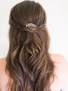 Elegante pettine da sposa con foglie di cristallo dorato indossato su capelli mossi castani