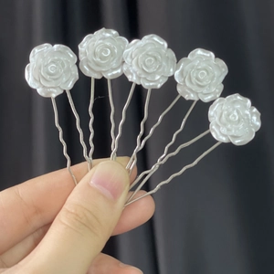Detailed close-up of five white camellia hair clips with silver wavy U-shaped pins