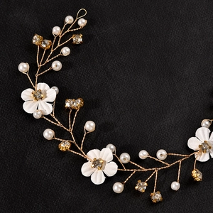 Detailed macro view of white fabric flowers and sparkling rhinestones on golden bridal headpiece