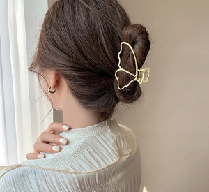 Détail d'une pince à cheveux papillon en métal doré KC pour une coiffure élégante et chic