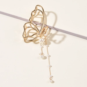 Detail of golden butterfly hair claw clip with elegant pearl tassels and openwork design