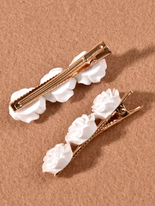 Detail view of two vintage camellia hair clips with white resin roses and gold finish