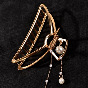 Detail of a golden metal hair claw clip featuring elegant hanging pearl fringe tassels