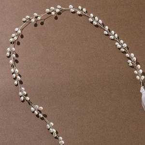 Elegant bridal hair vine with handmade white pearls and silver wire on brown backdrop