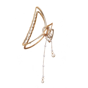 Detail of golden butterfly hair claw clip with elegant dangling pearl tassels and charms