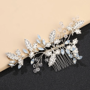 Macro detail of bridal hair comb featuring silver vines with rhinestones and opal beads