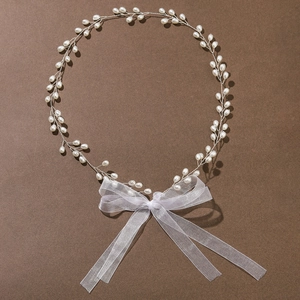 Elegant bridal pearl hair band with organza bow on a textured dark background