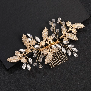 Close-up of golden bridal hair comb with rhinestone leaves and crystal beads