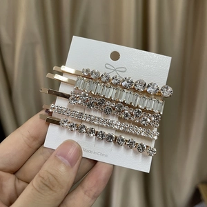 Vue détaillée de 5 barrettes dorées avec strass géométriques sur une carte blanche