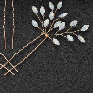 Macro detail of U-shaped bridal hair pin with milky leaf beads and gold woven wire