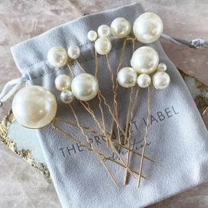 Set of 7 gold U-shaped hair pins with white pearls and a grey velvet storage pouch