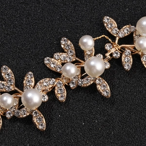 Detailed macro view of bridal hair piece with gold alloy leaves, pearls, and crystals