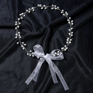 Elegant bridal pearl headband with white organza ribbon bow on black textured background