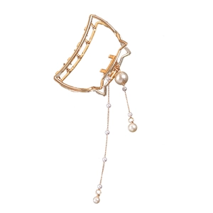 Detail of golden cat-shaped hair claw with elegant hanging pearl tassels and gold chains